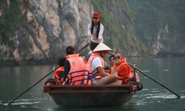 Boating tour on Halong Bay in Vietnam with tourists in a traditional wooden boat.