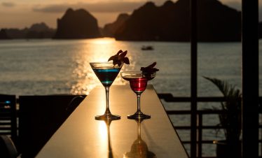 Colorful cocktails at sunset on a seaside balcony, tropical vacation drinks with ocean view.