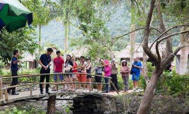 Vietname tour group exploring lush jungle scenery at a traditional village bridge in Vietnam.