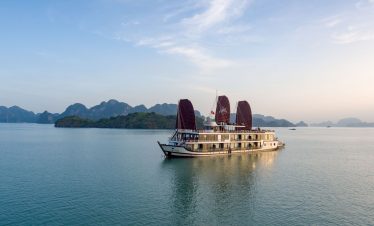 Luxury cruise boat sailing in Ha Long Bay, Vietnam, scenic limestone islands and emerald waters, eco-friendly tourism.