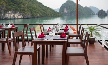 Luxurious boat dining setup with scenic gulf view and elegant table arrangements.
