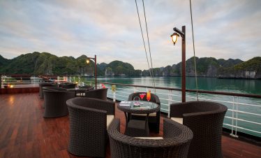 Relaxing outdoor cruise deck with scenic mountains and water view, perfect for tropical vacations.