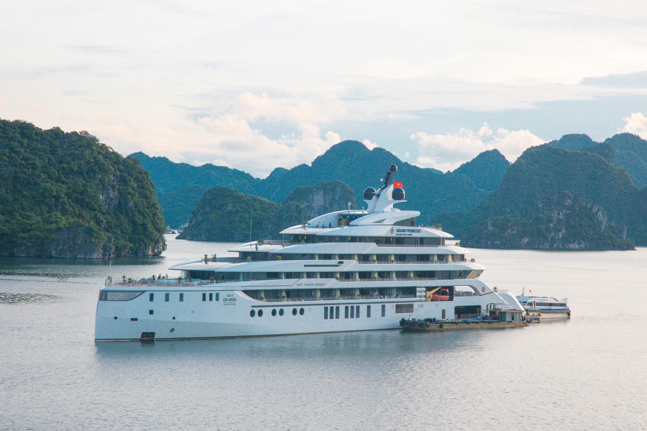 Luxurious cruise ship sailing in scenic Halong Bay, Vietnam, with green islands in the background.