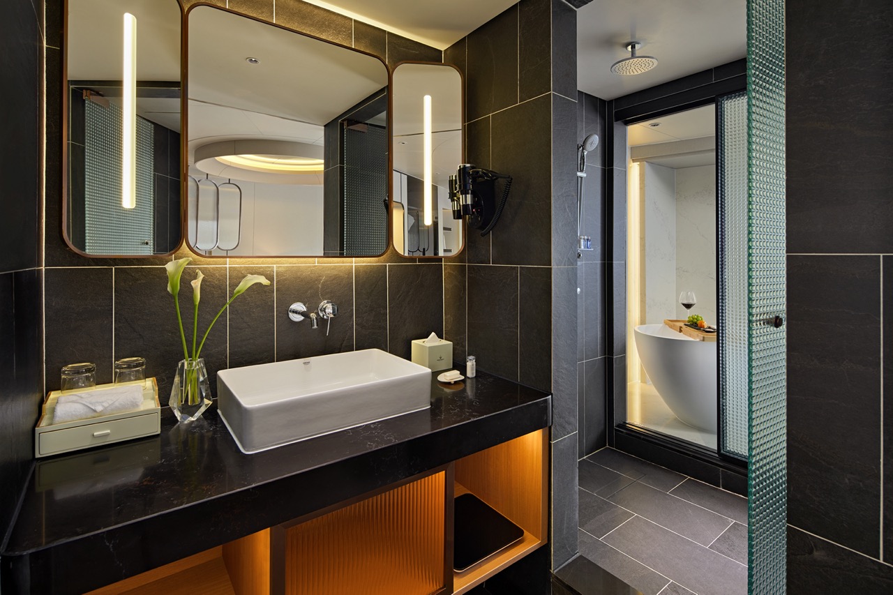 Luxurious modern bathroom with black tiles, stylish vanity, and elegant bathtub, perfect for a relaxing getaway.