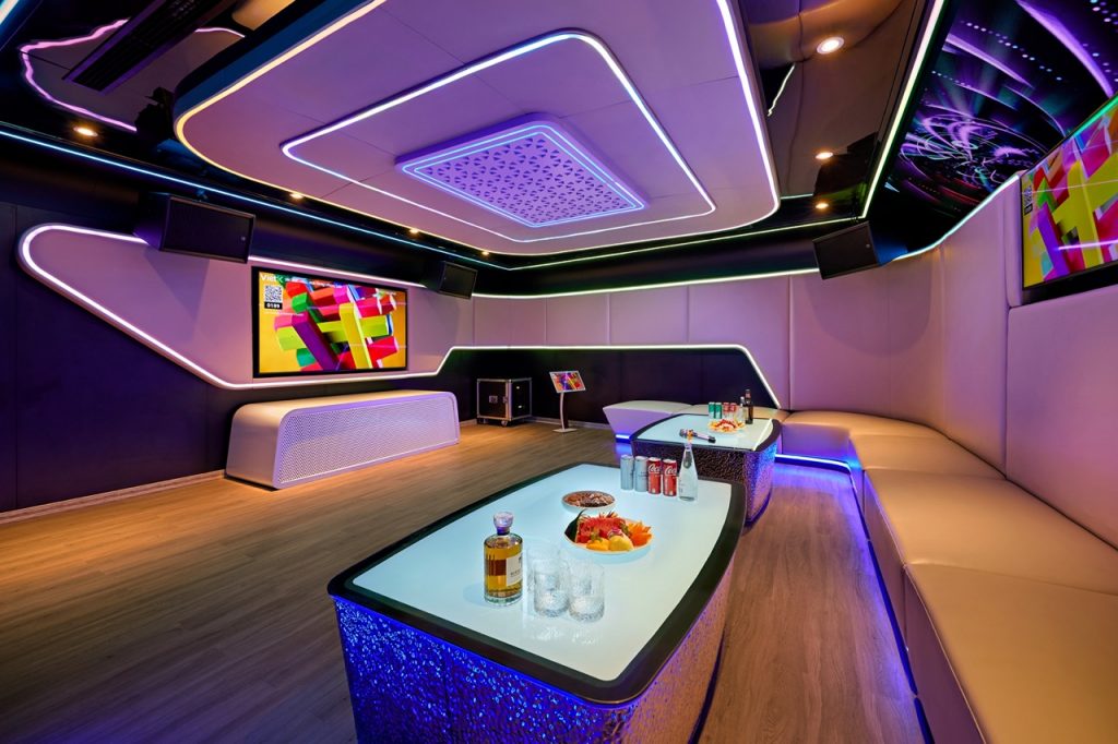 A modern luxury karaoke room with vibrant LED lighting and comfortable seating for entertainment.