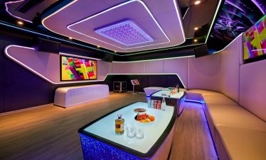 A modern luxury karaoke room with vibrant LED lighting and comfortable seating for entertainment.