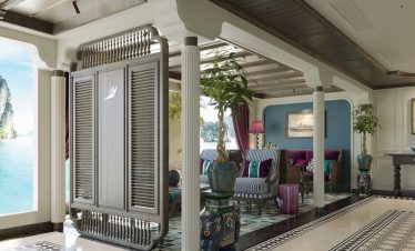 Luxurious tropical hotel lobby with ocean view, elegant furniture, and vibrant decor.