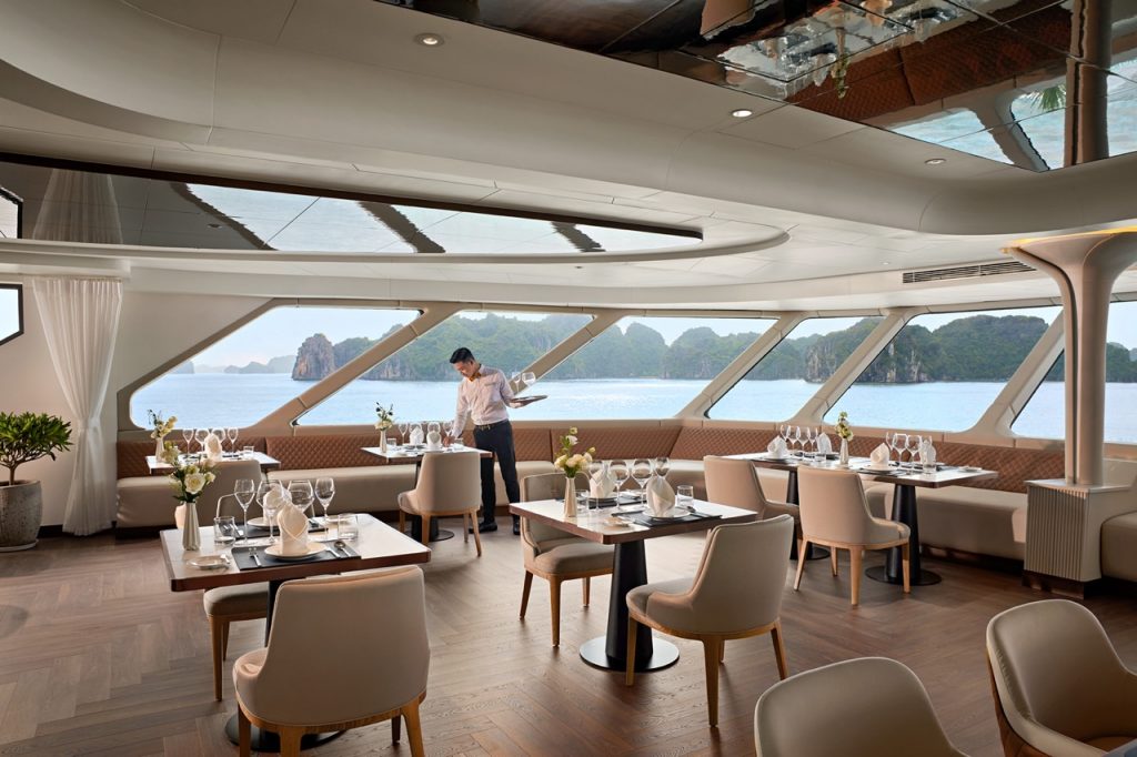 Luxurious cruise dining room with ocean views and elegant table settings.