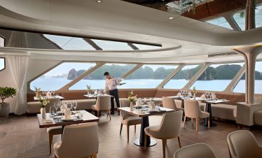 Luxurious cruise dining room with ocean views and elegant table settings.