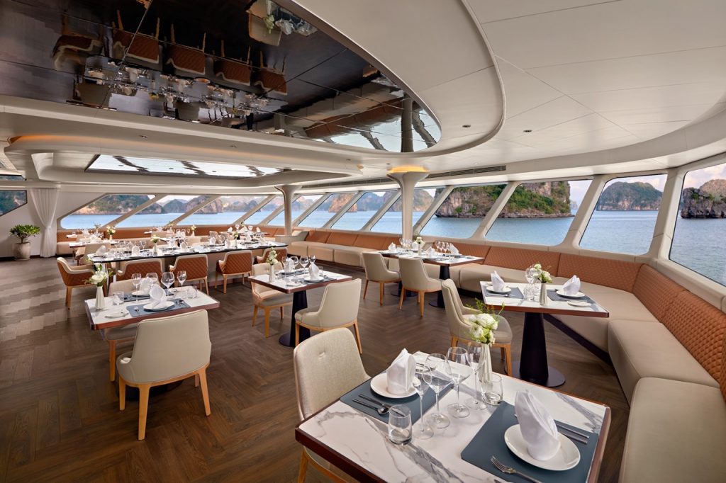 Luxurious cruise ship dining area overlooking ocean with modern decor and elegant table settings.