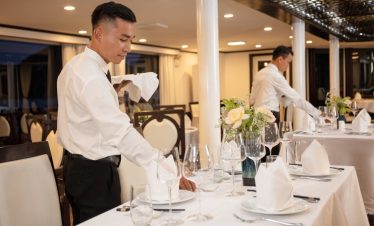 Elegant restaurant setting with waiters preparing tables for fine dining experience.