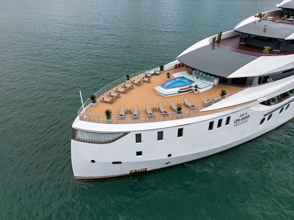 Luxurious yacht deck with a hot tub and sun loungers on the ocean.