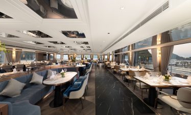 Luxurious yacht dining room with elegant seating and panoramic waterfront views.