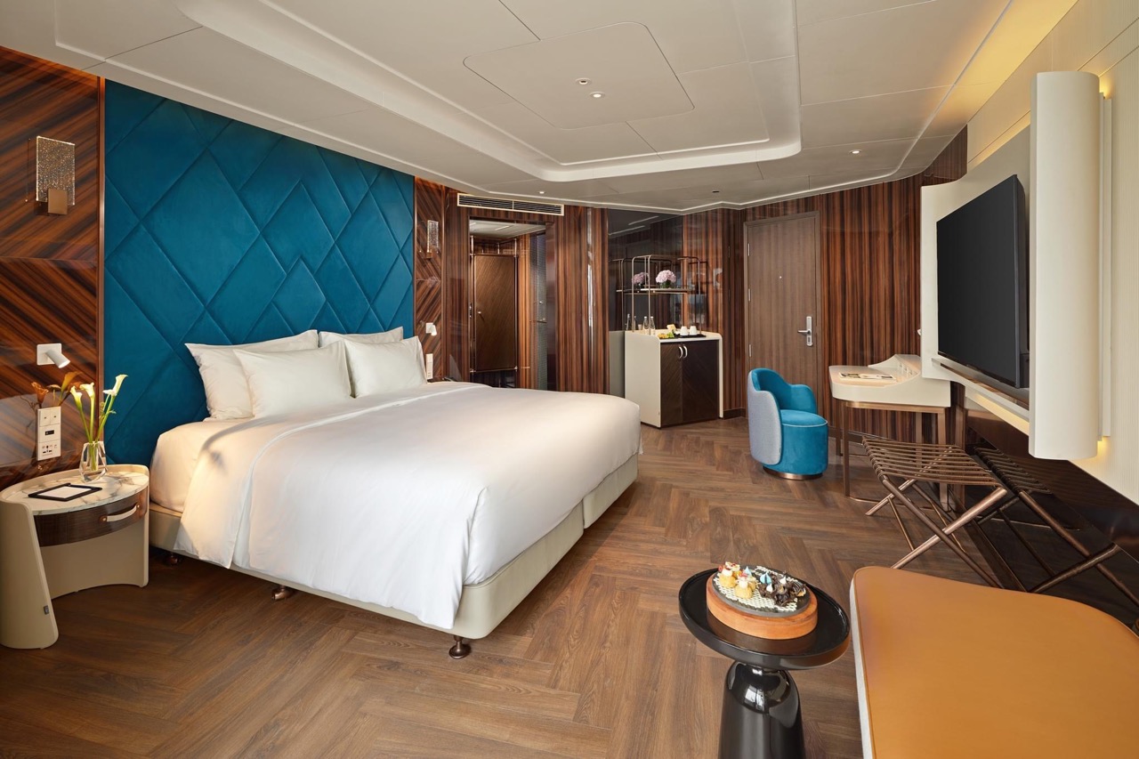 Luxurious hotel bedroom with modern decor, king-sized bed, and elegant wood accents.