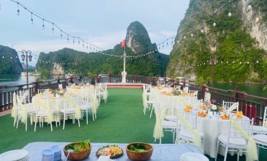 Lakeside boat dinner with elegant tables, string lights, and scenic limestone mountains in Vietnam.