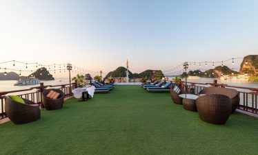 Breathtaking view of a cruise deck with lounge chairs overlooking Ha Long Bay, Vietnam.