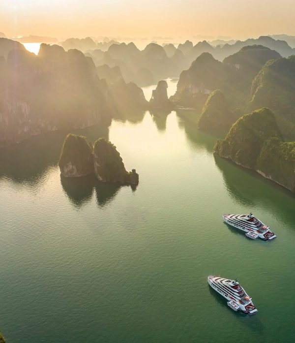 Vietnameses natural landscape with limestone karsts and cruising boats at sunset.