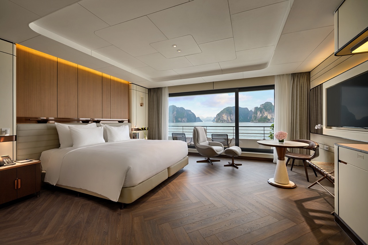 Luxurious hotel bedroom with mountain and sea view, modern decor, and cozy seating area.