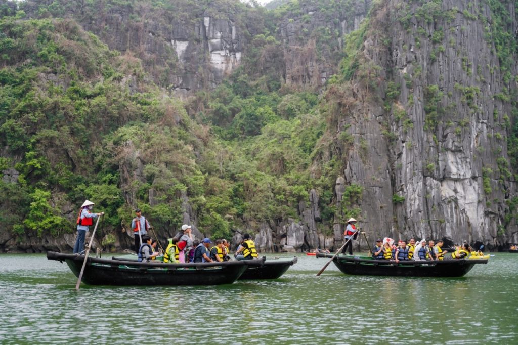 Relaxing boat tour in Ha Long Bay with tourists and scenic limestone cliffs.