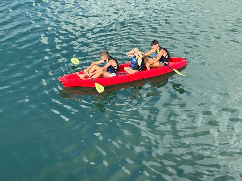 Kids kayaking adventure in clear water with safety vests and paddles for fun outdoor activity.