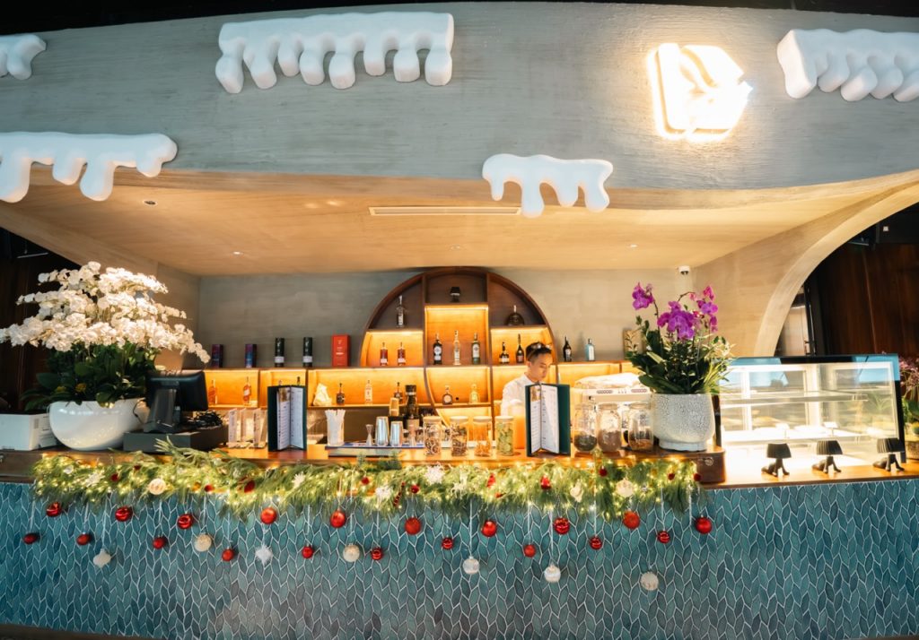 Cozy hotel bar decorated with festive garlands, flowers, and holiday ornaments for Christmas.