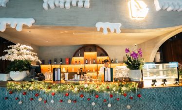 Cozy hotel bar decorated with festive garlands, flowers, and holiday ornaments for Christmas.