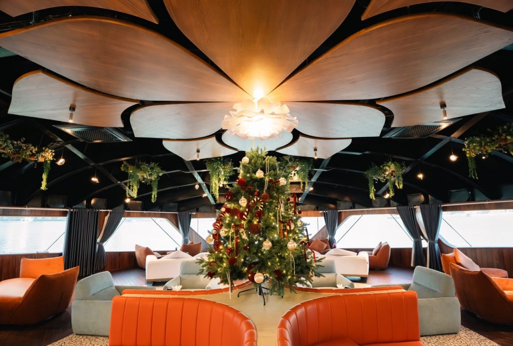 Cozy boat interior with Christmas decorations, plush seating, and scenic water views.