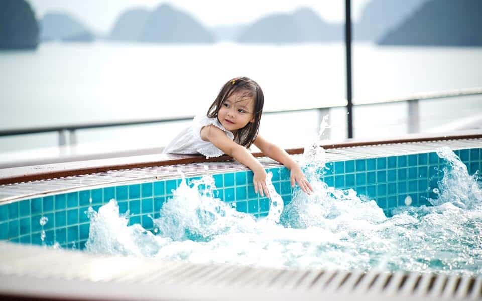 Child playing in hot spring pool with scenic mountain and lake view in Vietnam.