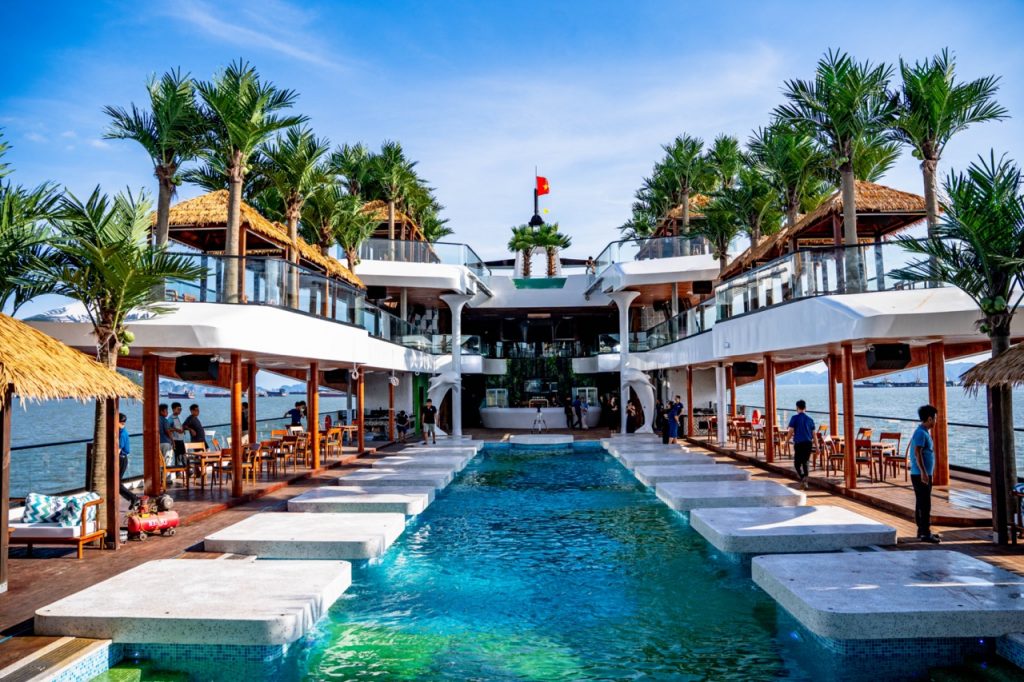 Luxurious waterfront resort with infinity pool, palm trees, and ocean views in Vietnam.