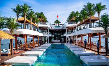 Luxurious waterfront resort with infinity pool, palm trees, and ocean views in Vietnam.