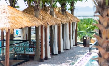 Luxurious beach cabanas with palm trees and ocean view.