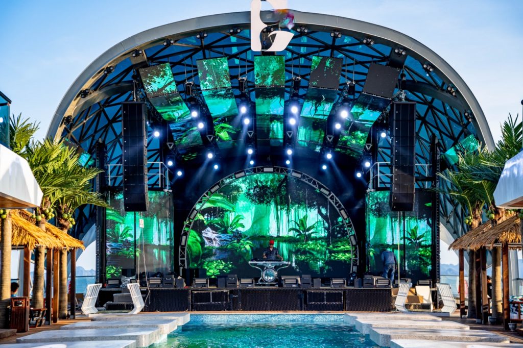 ViettrendTour, tropical outdoor concert stage with vibrant LED screens and lush greenery backdrop.