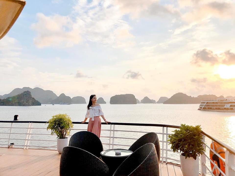 Breathtaking ocean view with woman enjoying sunset from cruise deck at Halong Bay.