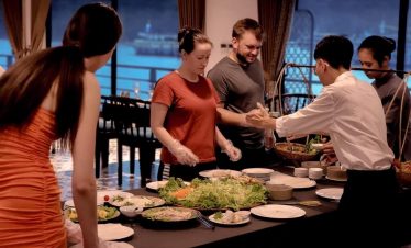People enjoying a delicious meal on cruise in Lan Ha Bay, Vietnam, with scenic water views in the ba.