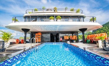 Stunning view of a modern cruise ship with a swimming pool on Lan Ha Bay, surrounded by lush green i.
