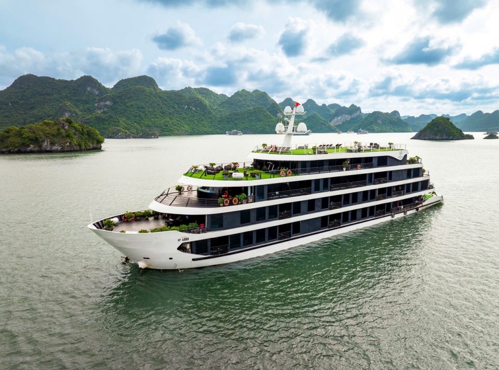 Luxury cruise ship sailing in Lan Ha Bay with scenic limestone islands and emerald waters.