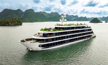 Luxury cruise ship sailing in Lan Ha Bay with scenic limestone islands and emerald waters.