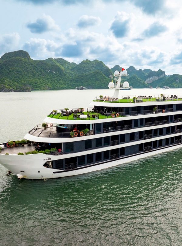 Luxury cruise ship sailing in Lan Ha Bay with scenic limestone islands and emerald waters.