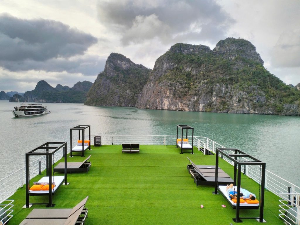 Scenic Lan Ha Bay cruise deck with loungers and mountain backdrop, perfect for relaxing and enjoying.