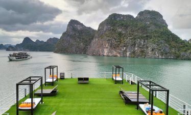 Scenic Lan Ha Bay cruise deck with loungers and mountain backdrop, perfect for relaxing and enjoying.