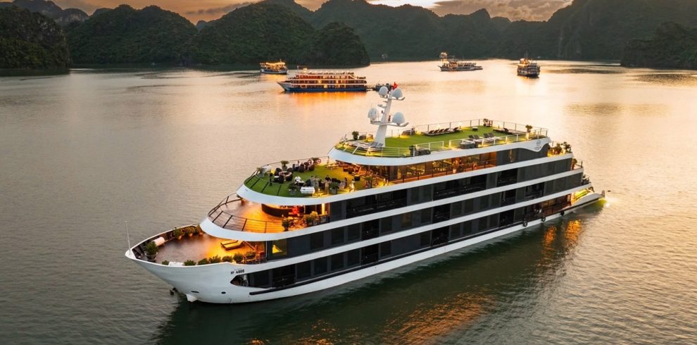 Luxury cruise ship sailing in Lan Ha Bay with scenic limestone karsts at sunset.