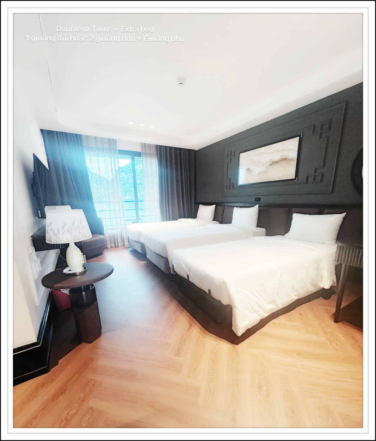 Hotel room featuring two double beds with white linens, dark accent wall, and wall art above the beds.