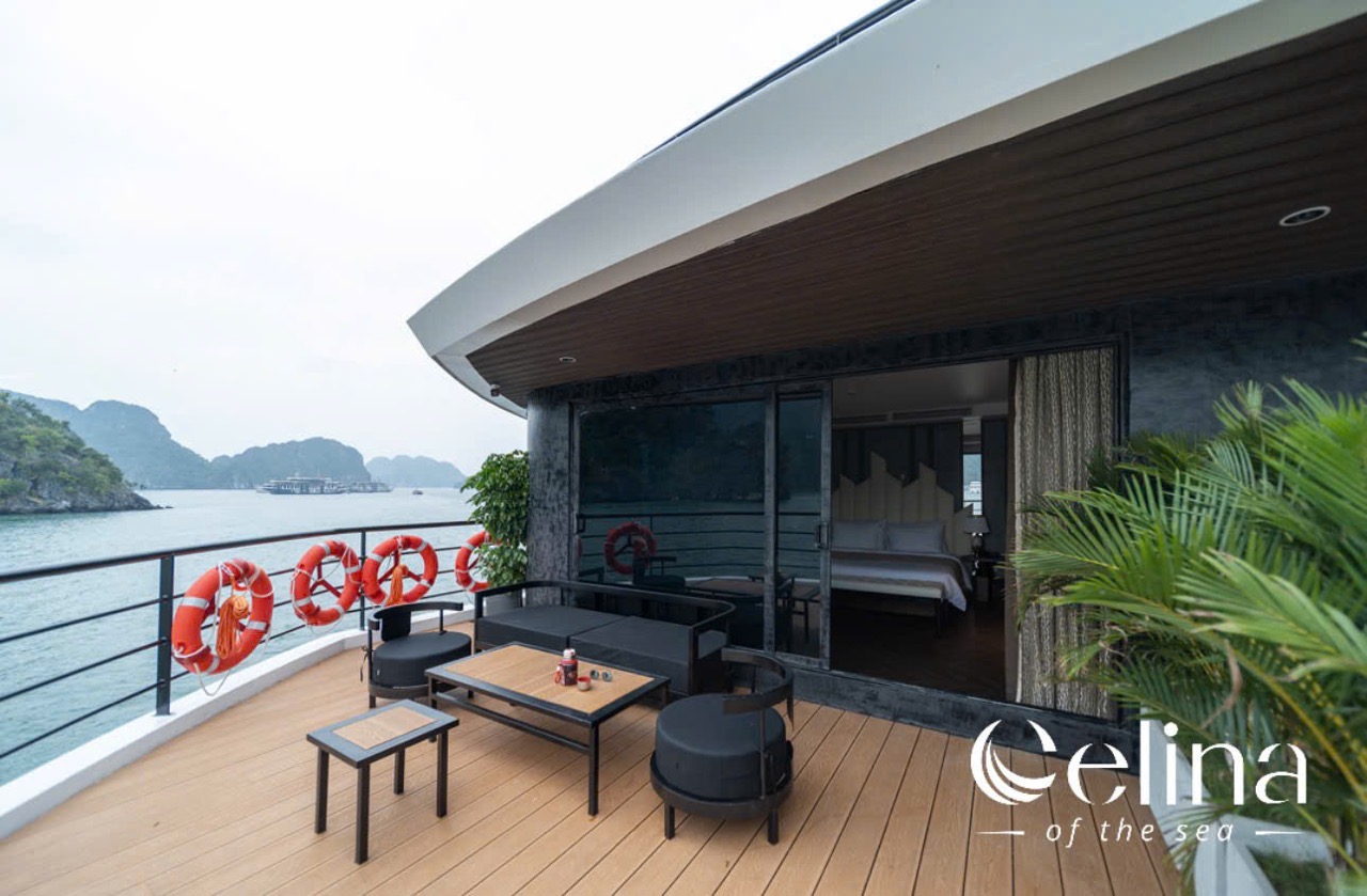 Outdoor seaside hotel terrace with seating area, life rings on railing, and sliding doors opening to a bedroom; Celina of the sea logo visible.