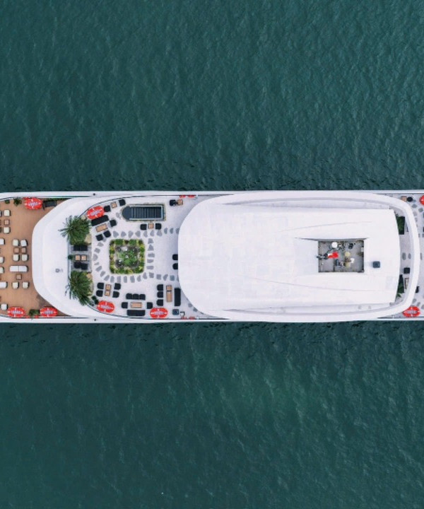 Aerial view of a large white luxury yacht cruising on calm blue water, seen from above.