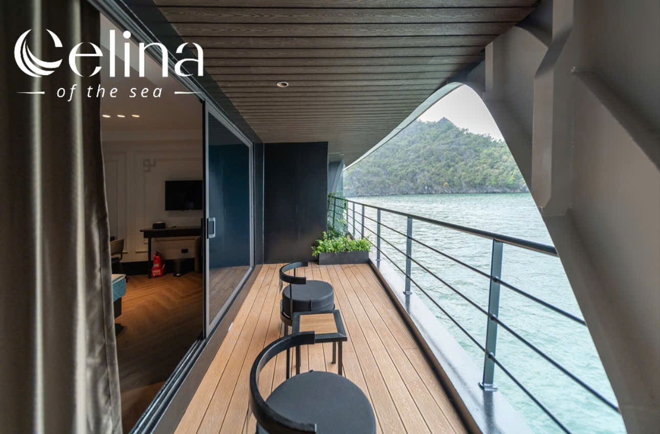 Yacht balcony on a wooden deck with two black stools, railing, and a view of calm water and green hills; Celina of the sea logo in the top-left.