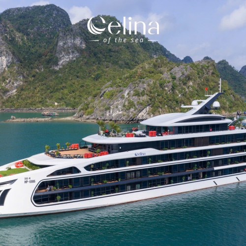 Luxurious white multi-deck yacht Celina of the Sea anchored in a turquoise bay with green limestone cliffs in the background.
