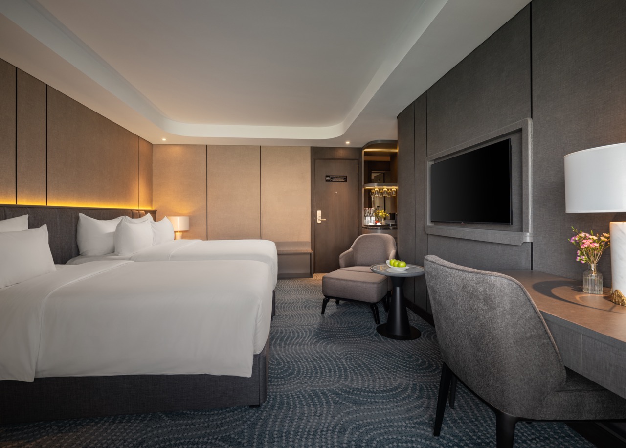 Hotel room with two large beds, white linens, and soft ambient lighting along headboards.