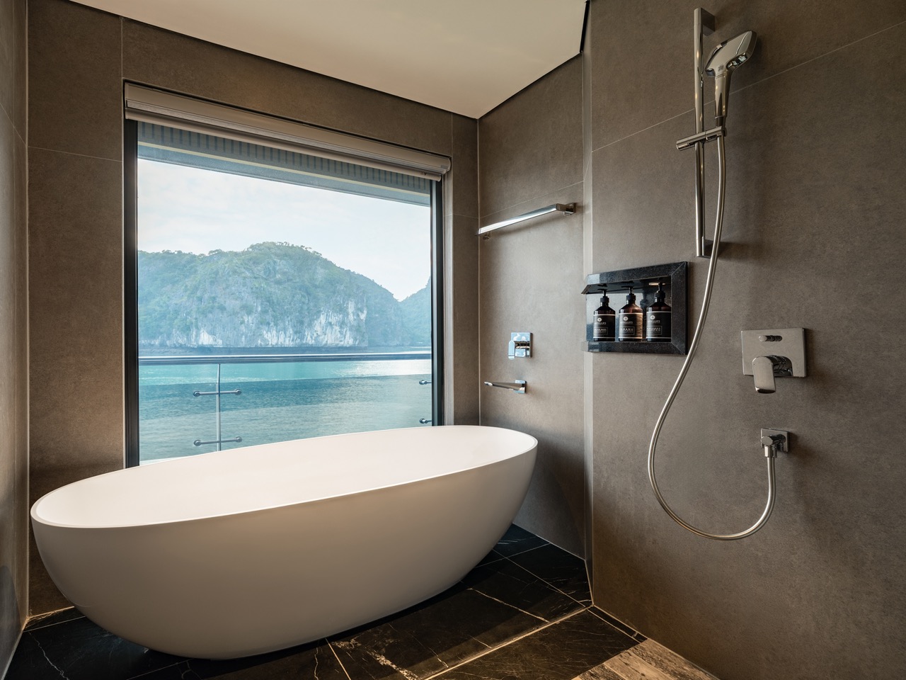 White oval freestanding bathtub by a large window with an ocean and cliff view