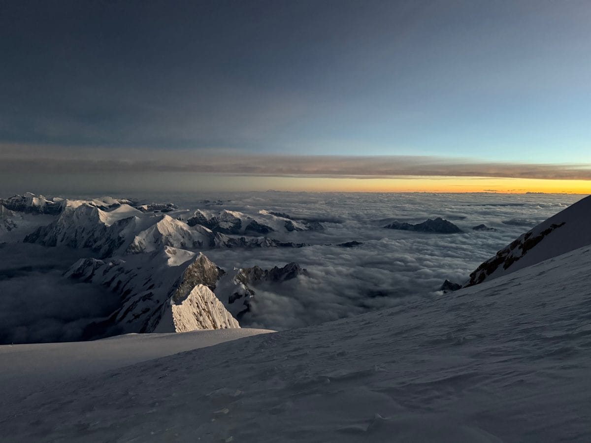 A breathtaking view of snow-capped mountains above a sea of clouds during sunrise, showcasing the tranquil beauty of nature.