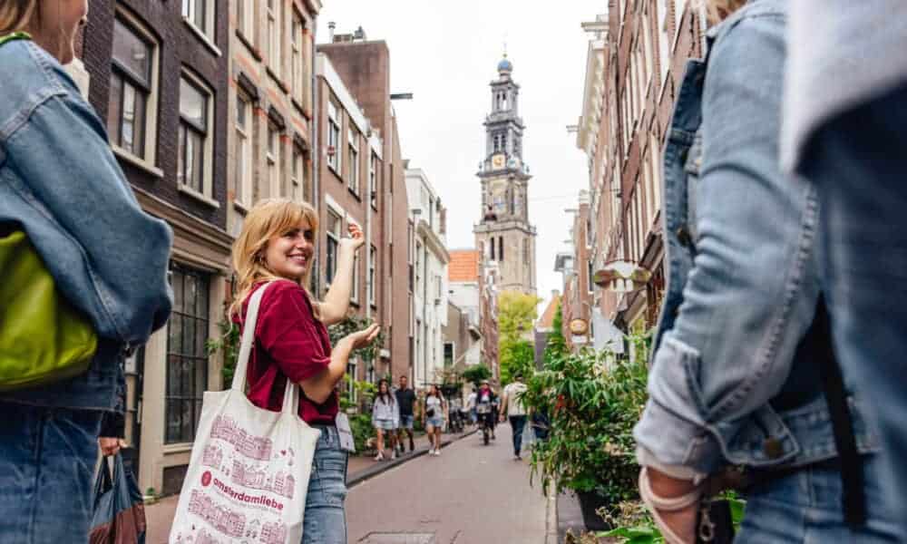 Tourists on a city trip in Amsterdam. A woman with a red shirt and a white bag.